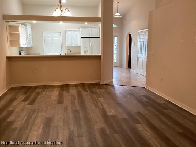 interior space featuring dark wood-style flooring, arched walkways, a sink, baseboards, and lofted ceiling