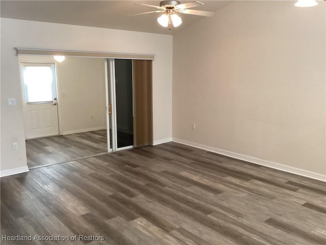 unfurnished bedroom featuring dark wood-style flooring, baseboards, ceiling fan, and a closet