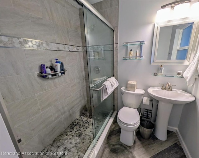 bathroom with toilet, sink, and a shower with shower door