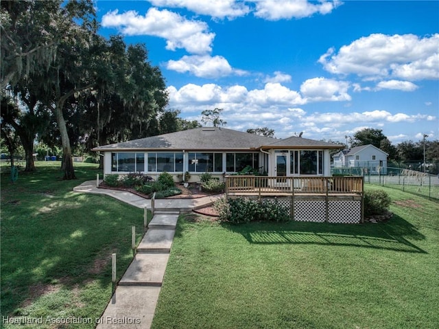 back of property with a lawn, a wooden deck, and a sunroom