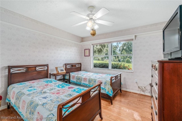 bedroom featuring ceiling fan, light hardwood / wood-style floors, and a textured ceiling