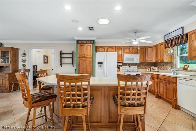 kitchen with backsplash, ornamental molding, white appliances, light tile patterned floors, and a kitchen island