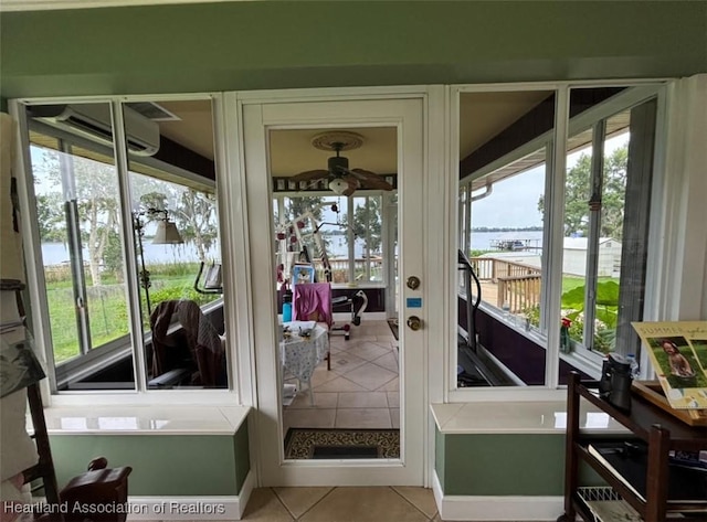 doorway with a wall unit AC, a water view, ceiling fan, and light tile patterned floors