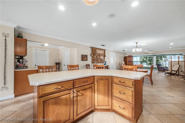 kitchen featuring ceiling fan, a kitchen island, light tile patterned floors, and crown molding