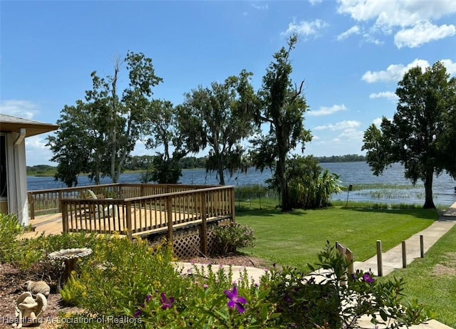 view of property's community featuring a lawn and a deck with water view