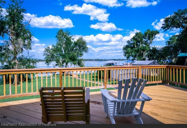 wooden terrace with a water view and a lawn