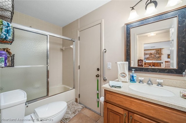 full bathroom with shower / bath combination with glass door, vanity, tile patterned floors, and toilet