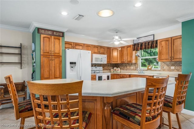 kitchen with ceiling fan, a center island, white appliances, light tile patterned flooring, and ornamental molding