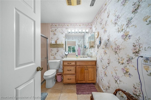 bathroom featuring tile patterned floors, vanity, a textured ceiling, a shower with door, and toilet