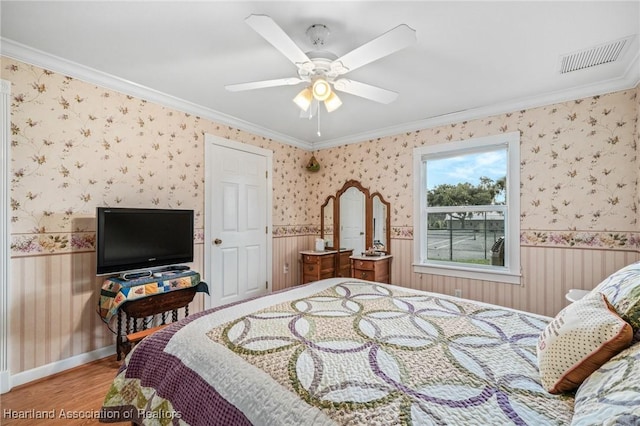 bedroom with ceiling fan, hardwood / wood-style floors, and ornamental molding