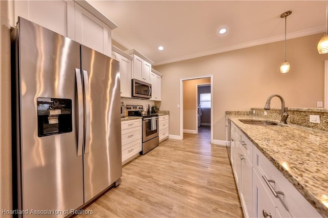 kitchen with pendant lighting, white cabinets, sink, light stone countertops, and appliances with stainless steel finishes