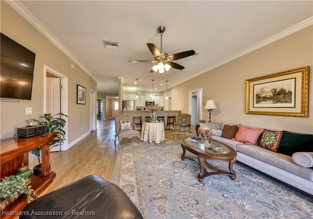 living room featuring ceiling fan, light wood-type flooring, and ornamental molding