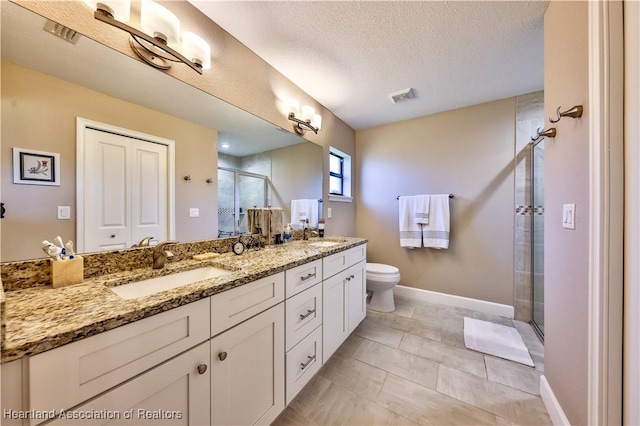 bathroom with tile patterned floors, vanity, a textured ceiling, a shower with door, and toilet