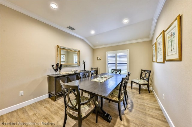 dining area featuring crown molding, light hardwood / wood-style flooring, and vaulted ceiling