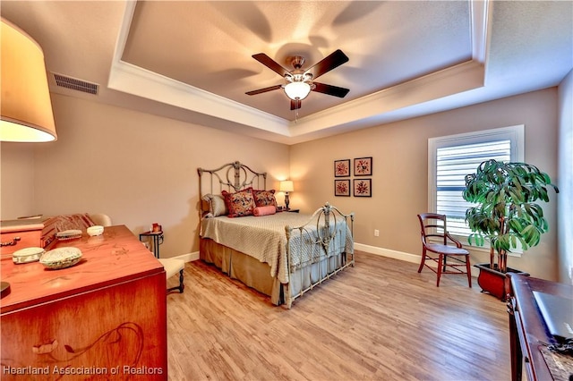 bedroom with a raised ceiling, ceiling fan, and light hardwood / wood-style floors