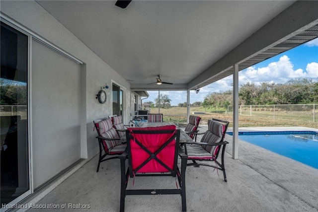 view of patio with a ceiling fan, a fenced in pool, fence, and outdoor dining space