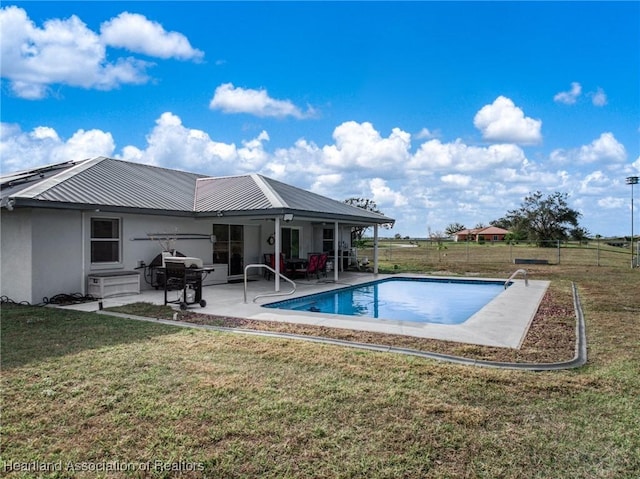 view of swimming pool featuring fence, a fenced in pool, grilling area, a lawn, and a patio area