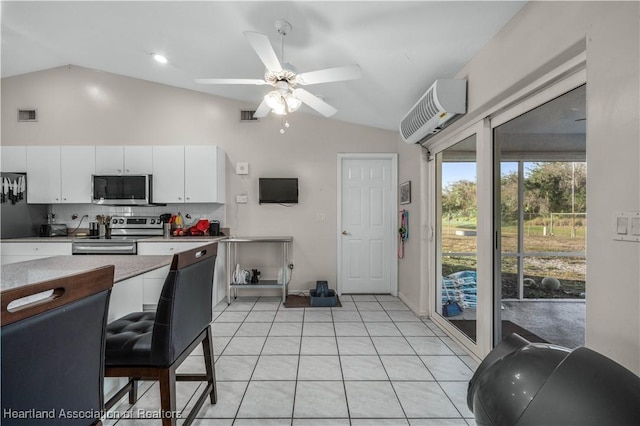 kitchen with a wall mounted air conditioner, visible vents, vaulted ceiling, and appliances with stainless steel finishes