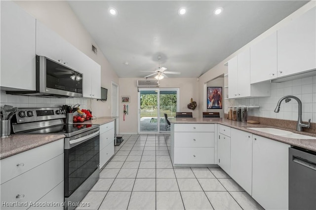 kitchen featuring light tile patterned flooring, a peninsula, appliances with stainless steel finishes, white cabinetry, and a sink