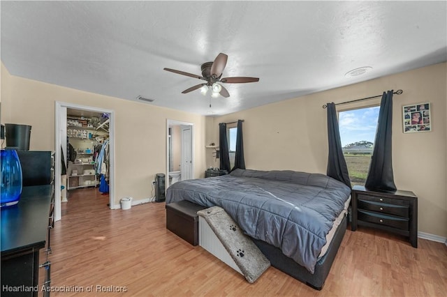 bedroom with a spacious closet, a closet, light wood-style floors, and visible vents