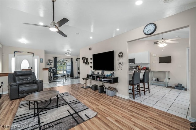 living room with ceiling fan, vaulted ceiling, and light wood finished floors