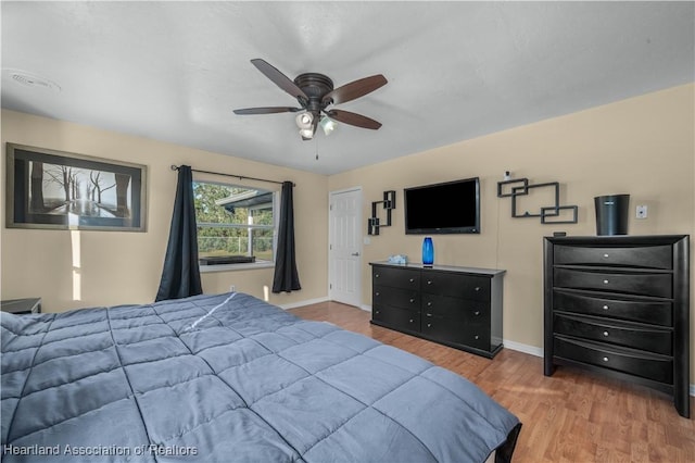 bedroom with a ceiling fan, baseboards, and wood finished floors