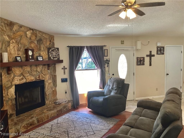 living area featuring a textured ceiling, a fireplace, a ceiling fan, and baseboards