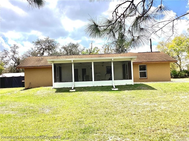 rear view of house featuring a yard and stucco siding