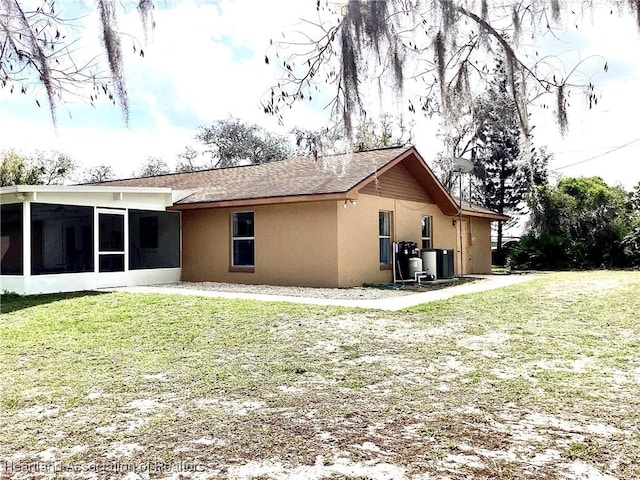 rear view of property with a sunroom, a yard, and stucco siding