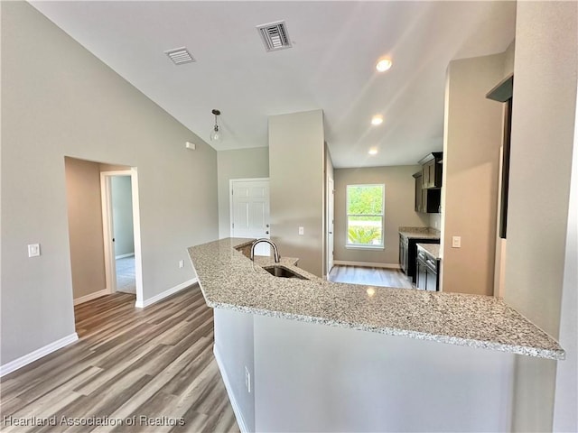 kitchen featuring light stone countertops, sink, high vaulted ceiling, and light hardwood / wood-style flooring