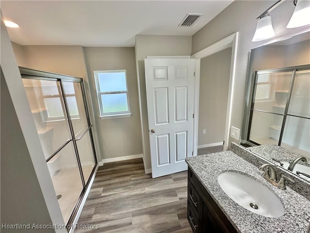 bathroom with vanity, wood-type flooring, and a shower with door