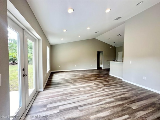 unfurnished living room featuring french doors, light wood-type flooring, and vaulted ceiling