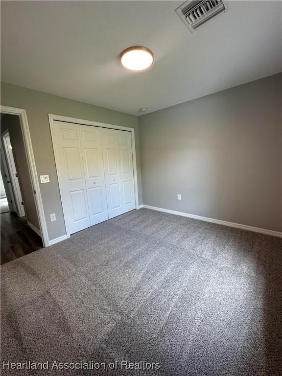 unfurnished bedroom featuring dark carpet and a closet