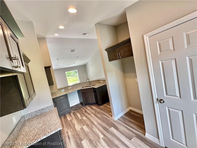 kitchen with dark brown cabinetry, light stone countertops, light hardwood / wood-style flooring, and sink