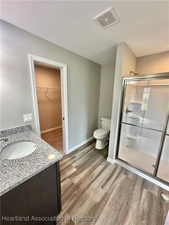 bathroom featuring hardwood / wood-style flooring, vanity, toilet, and a shower with door