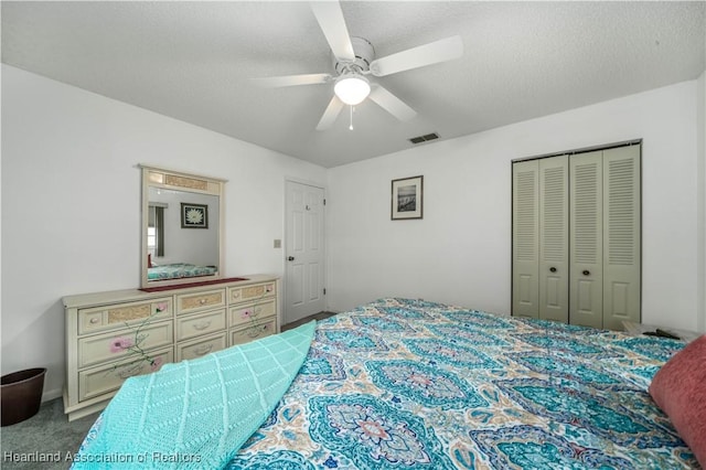 bedroom with carpet flooring, ceiling fan, a closet, and a textured ceiling