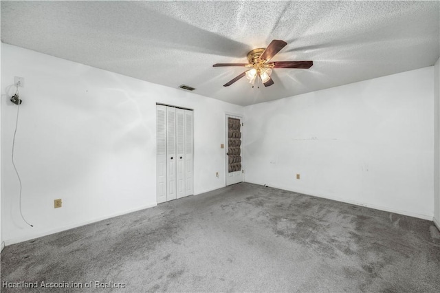 carpeted empty room featuring ceiling fan and a textured ceiling