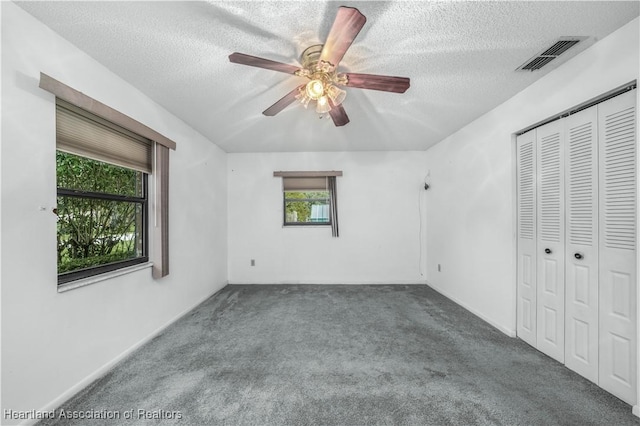 unfurnished bedroom with carpet, ceiling fan, a textured ceiling, and a closet