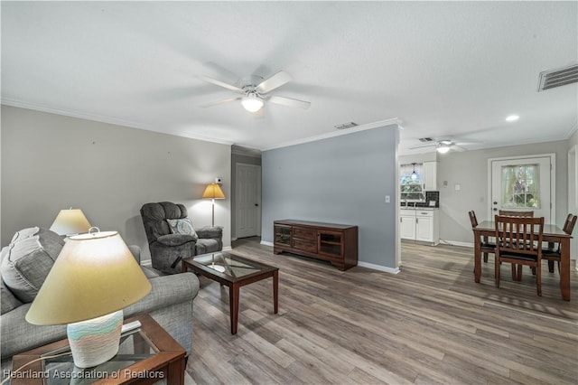 living room with hardwood / wood-style floors, ceiling fan, and crown molding