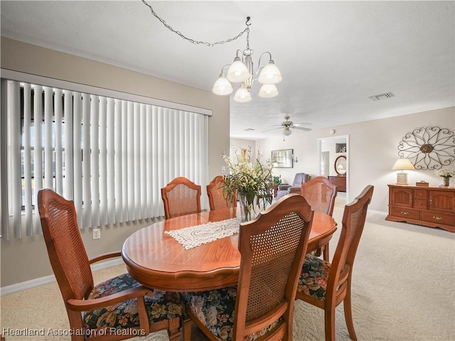 dining area with ceiling fan with notable chandelier and light carpet