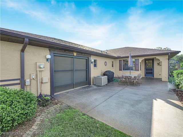 back of house with a garage, a patio, and central air condition unit