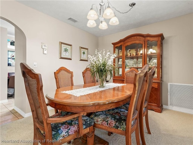 dining area featuring light colored carpet and a notable chandelier