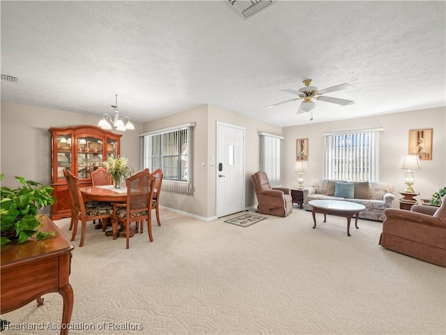 carpeted living room featuring ceiling fan with notable chandelier and a textured ceiling