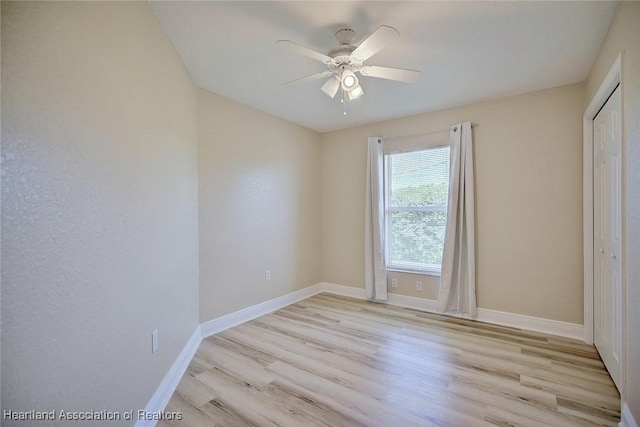 spare room featuring light wood finished floors, baseboards, and a ceiling fan