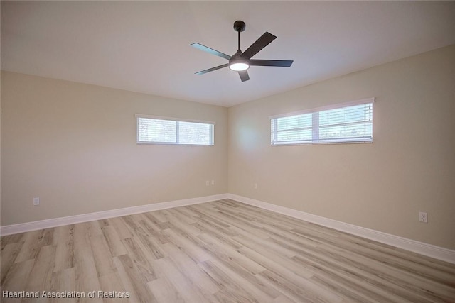 spare room with ceiling fan, light wood finished floors, and baseboards