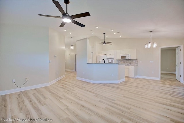 unfurnished living room with lofted ceiling, ceiling fan with notable chandelier, baseboards, and light wood-style floors