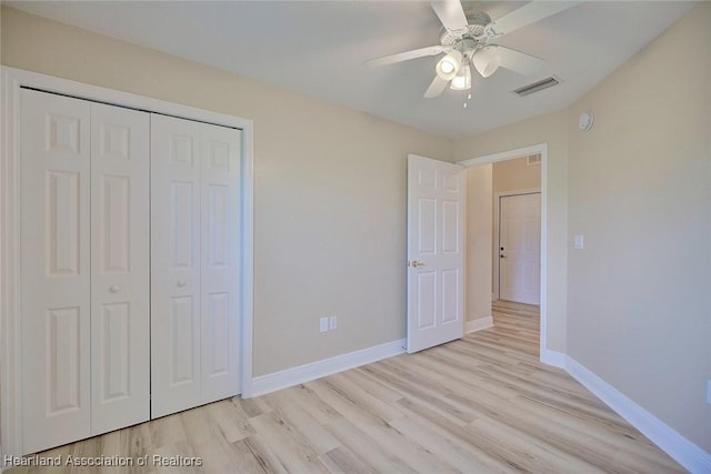 unfurnished bedroom featuring light wood finished floors, baseboards, visible vents, and a closet