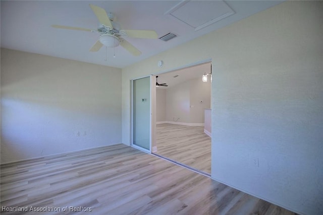 unfurnished bedroom with a ceiling fan, wood finished floors, visible vents, and attic access