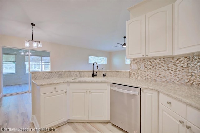 kitchen with light wood finished floors, decorative backsplash, white cabinets, a sink, and dishwasher