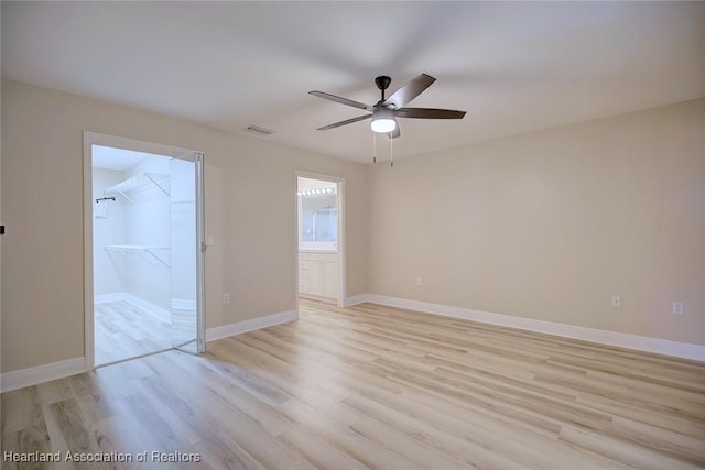 unfurnished room with visible vents, light wood-type flooring, a ceiling fan, and baseboards